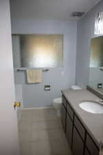 Bathroom with tile patterned floors, vanity, toilet, and a tub