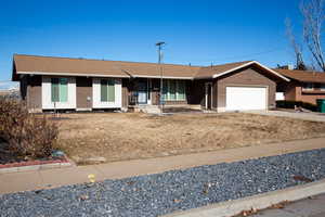 Ranch-style house featuring a garage and a front lawn