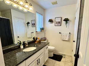 Bathroom featuring vanity, toilet, tile patterned flooring, and a textured ceiling