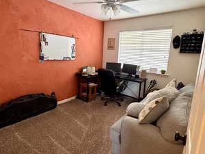 Carpeted home office with a textured ceiling and ceiling fan