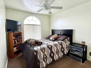 Bedroom with carpet floors, a textured ceiling, and ceiling fan