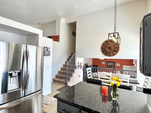 Kitchen featuring light tile patterned flooring, decorative light fixtures, dark stone countertops, stainless steel appliances, and a textured ceiling