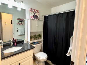 Bathroom featuring vanity, toilet, tile patterned flooring, and a textured ceiling