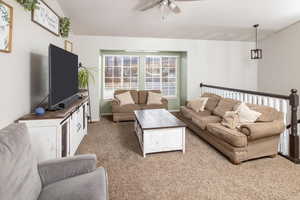 Living room featuring vaulted ceiling, light carpet, and ceiling fan