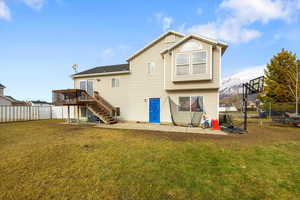 Back of property with a wooden deck, a yard, and a patio