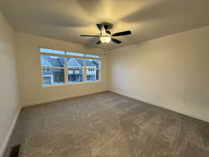 Carpeted spare room with a textured ceiling and ceiling fan