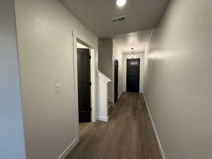 Corridor with hardwood / wood-style flooring and a chandelier