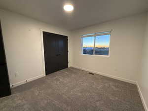 Unfurnished bedroom featuring dark colored carpet and a closet