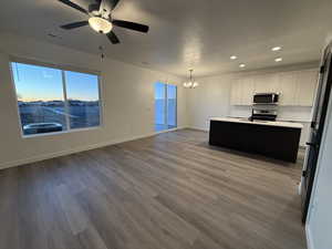 Kitchen featuring white cabinetry, stainless steel appliances, light hardwood / wood-style floors, and an island with sink