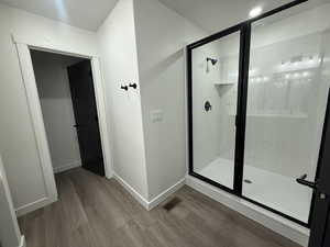 Bathroom with hardwood / wood-style flooring and a shower with shower door