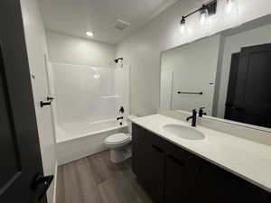 Full bathroom with hardwood / wood-style flooring, vanity, shower / bathtub combination, and toilet