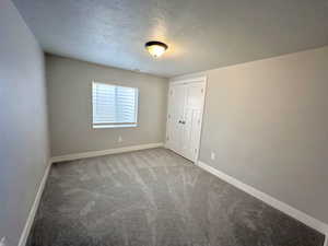 Carpeted spare room featuring a textured ceiling