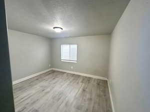 Spare room featuring a textured ceiling and light wood-type flooring