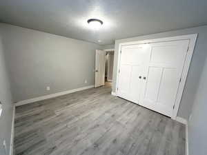 Unfurnished bedroom with light hardwood / wood-style floors, a closet, and a textured ceiling