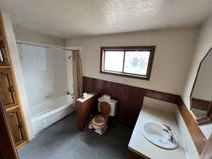 Full bathroom with shower / bath combination with curtain, vanity, toilet, and a textured ceiling