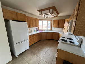 Kitchen featuring white appliances, sink, and light tile patterned floors