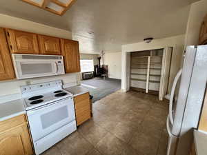 Kitchen featuring white appliances, radiator heating unit, light tile patterned floors, and a wood stove