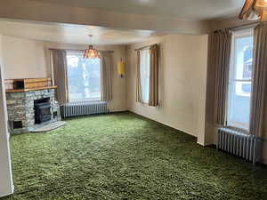 Unfurnished living room featuring radiator and carpet