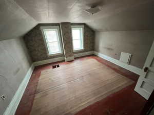 Bonus room with lofted ceiling and wood-type flooring