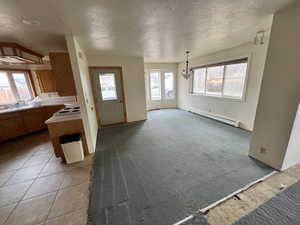 Interior space with a baseboard radiator, light carpet, and a textured ceiling