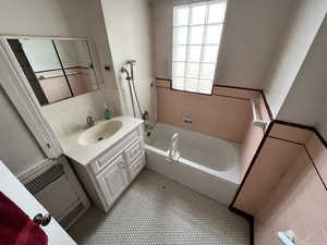 Bathroom with vanity, radiator, and bathtub / shower combination