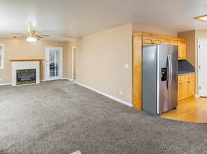 Kitchen with a tiled fireplace, stainless steel refrigerator with ice dispenser, light colored carpet, and light brown cabinetry