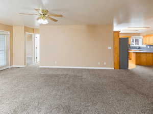 Unfurnished living room with light carpet and ceiling fan