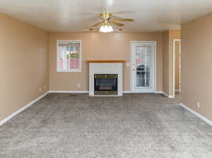 Unfurnished living room featuring carpet floors, a fireplace, and ceiling fan