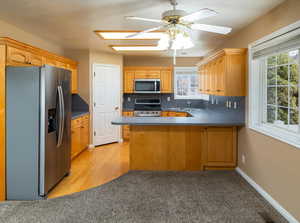 Kitchen with sink, tasteful backsplash, appliances with stainless steel finishes, kitchen peninsula, and ceiling fan