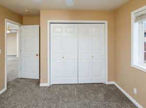 Unfurnished bedroom featuring ceiling fan, a closet, and carpet