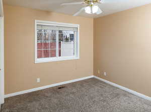 Carpeted spare room featuring ceiling fan