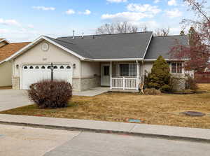 Single story home featuring a porch, a garage, and a front yard