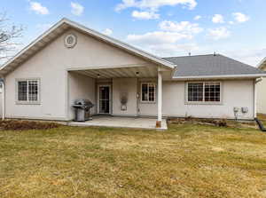 Rear view of house with a patio and a lawn