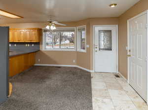 Kitchen with light tile patterned floors, stainless steel fridge, and ceiling fan