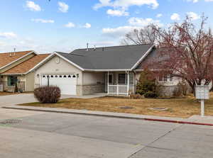 View of front facade featuring a garage, a porch, and a front yard