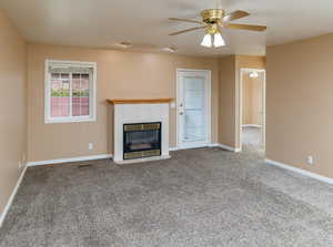 Unfurnished living room featuring ceiling fan, a fireplace, and carpet flooring