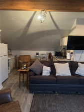 Living room with sink, light lamintae flooring, and vaulted ceiling.