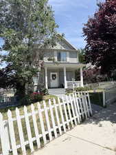 View of front of property featuring covered porch and a fenced front yard