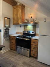 knotty alder cabinets,  white refrigerator, laminate floors, and stainless steel range with electric stovetop.