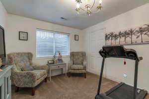 Workout room featuring carpet floors and a chandelier