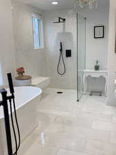 Bathroom featuring shower with marble separate bathtub.  Mother of pearl shower walls & large chandelier.