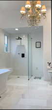 Full bath with a soaking tub, baseboards, and a walk in shower in marble.