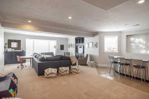 Carpeted living room with bar, ornamental molding, and a textured ceiling