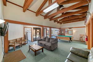 Carpeted living room featuring french doors, pool table, beam ceiling, and high vaulted ceiling