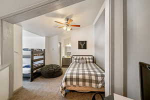 Bedroom featuring ceiling fan, ensuite bath, vaulted ceiling, and light carpet