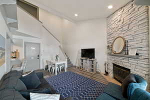 Living room featuring wood-type flooring, a towering ceiling, and a fireplace