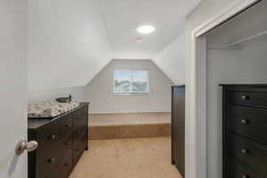 Walk in closet featuring light colored carpet and lofted ceiling