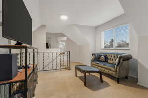 Living area with lofted ceiling and light carpet