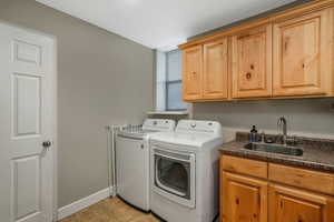 Clothes washing area with cabinets, sink, and independent washer and dryer