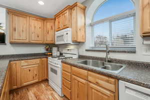 Kitchen featuring white appliances, light hardwood / wood-style floors, and sink